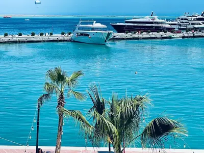 two boats are docked in a harbor with palm trees at New Marina Hurghada Suite in Hurghada