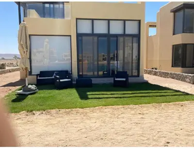 a house with chairs on the grass in front of it at Emos Villa in Hurghada