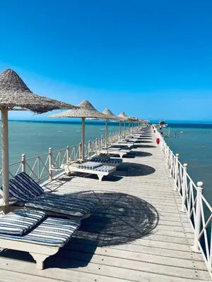 a pier with lounge chairs and umbrellas on the beach at Apartment in el karma aqua beach resort hurghada near El gouna in Hurghada