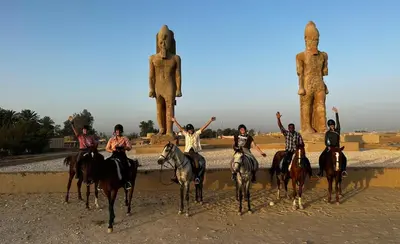 a group of people riding horses in front of statues at Green Palace Garden in Luxor