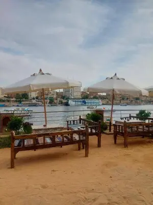a group of benches with umbrellas on a beach at ANA-KA Guest house in Aswan