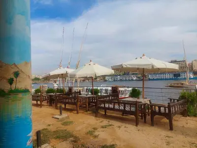 a row of tables and chairs with umbrellas next to the water at ANA-KA Guest house in Aswan