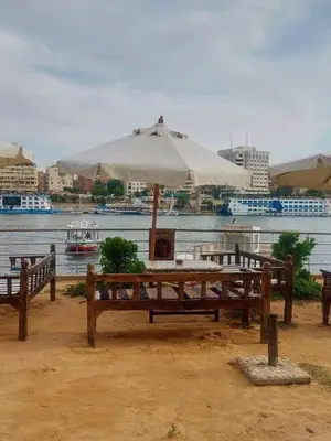 a picnic table with an umbrella next to the water at ANA-KA Guest house in Aswan