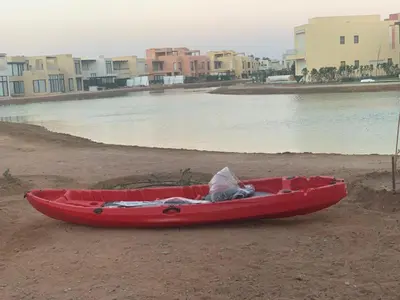 a red kayak sitting on a beach next to a body of water at Apartment in Tawila ElGouna The Butterfly in Hurghada