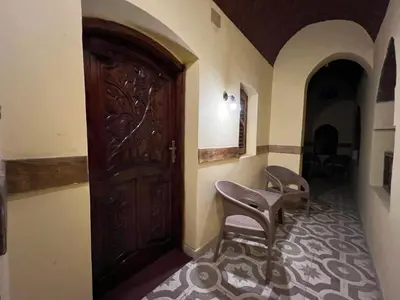 a hallway with a wooden door and two chairs at Elphardous Oasis Hotel in Luxor