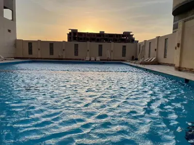 a large swimming pool in front of a building at Cozy Studio With Private Beach ! in Hurghada