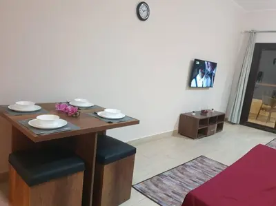 a dining room table with two stools and a table with plates on it at 3316- Awesome Garden view studio in Al Dau Heights in Hurghada