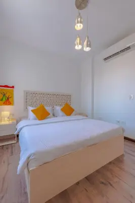 a white bedroom with a large bed with yellow pillows at 1BR with private Heated Jacuzzi at Sholan Elgouna in Hurghada