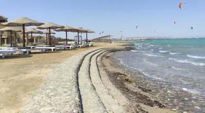 a beach with chairs and umbrellas and the ocean at Fanadir Bay Resort in Hurghada, Egypt in Hurghada