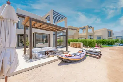 a house on the beach with a boat in front of it at Comfy 3BR Standalone in Tawila, El Gouna. Lagoon & Pool access in Hurghada