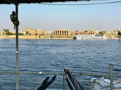 a boat in the water with a view of a city at Floating Hotel- Happy Nile Boat in Luxor