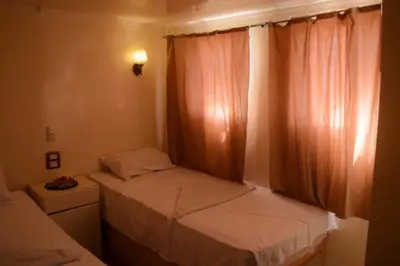 a small bedroom with two beds and a window at Floating Hotel- Happy Nile Boat in Luxor