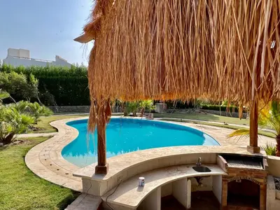 a swimming pool with a thatched umbrella and a swimming poolvisor at GS 23 in Hurghada