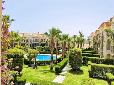 a garden with a swimming pool and palm trees and bushes at Stunning Pool View 1bed Private Beach Access, Veranda Sahl Hasheesh in Hurghada
