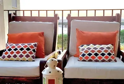 two chairs with pillows sitting on a porch at Stunning Pool View 1bed Private Beach Access, Veranda Sahl Hasheesh in Hurghada