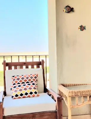a chair sitting on a porch with a pillow at Stunning Pool View 1bed Private Beach Access, Veranda Sahl Hasheesh in Hurghada