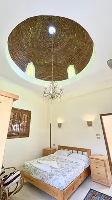 a bedroom with a large bed and a chandelier at Sunset Haven Guesthouse in Luxor