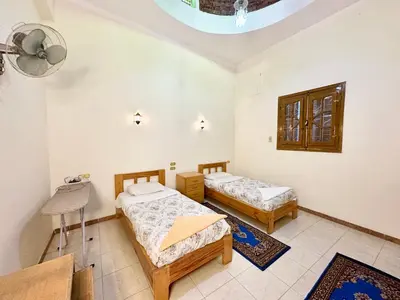 a bedroom with two beds and a table and a ceiling at Sunset Haven Guesthouse in Luxor
