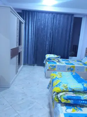 three beds in a room with blue curtains at Sun, Sea & Comfort in Hurghada