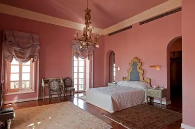 a bedroom with pink walls and a bed and a chandelier at La Maison Bleue El Gouna in Hurghada