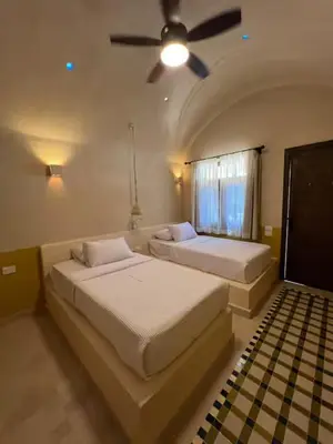 a bedroom with two beds and a ceiling fan at Ayujidda Nubian House in Aswan