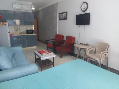 a living room with a couch and chairs and a kitchen at Makramia A107 studio in Hurghada