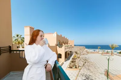 a woman in a white robe standing on a balcony at Akassia Swiss Resort in Quseir