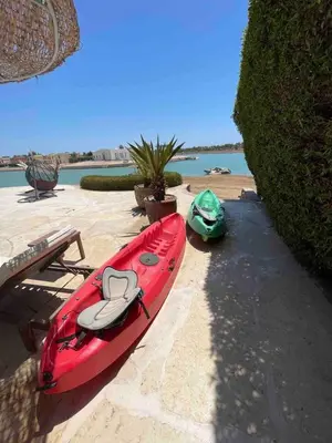 a red kayak sitting on the sand next to a bench at Spacious Villa with private pool-Gouna in Hurghada