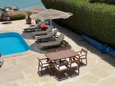 three chairs and a table with an umbrella next to a pool at Spacious Villa with private pool-Gouna in Hurghada
