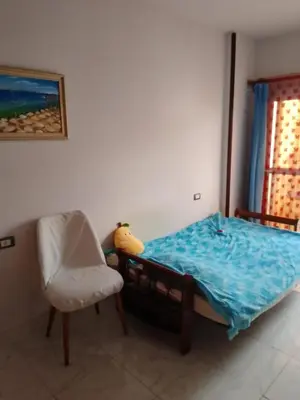 a bedroom with a bed and a chair and a window at Tiba View flat near pool in Hurghada