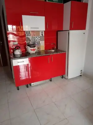 a red kitchen with a sink and a refrigerator at Tiba View flat near pool in Hurghada