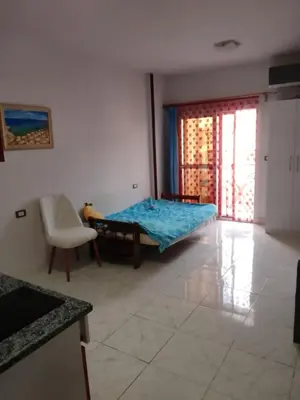 a bedroom with a bed and a chair and a window at Tiba View flat near pool in Hurghada