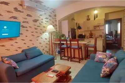 a living room with a blue couch and a kitchen at 1 Bed Apartment with Public Pool HotTub & PetsOk in Hurghada