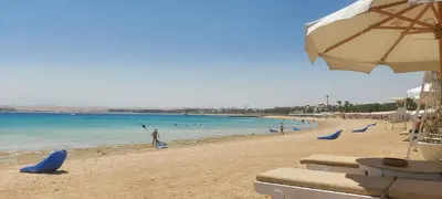 a beach with people playing in the water and an umbrella at 1 Bed Apartment with Public Pool HotTub & PetsOk in Hurghada