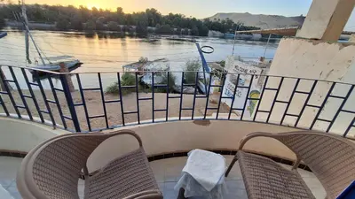 a balcony with two chairs and a view of the water at NOBATiA Guest House 2 in Aswan