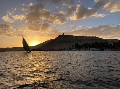 a sailboat in the water with a mountain in the background at Ajwa Guest House in Aswan