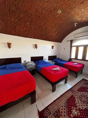 a bedroom with three beds with red and blue sheets at Ajwa Guest House in Aswan