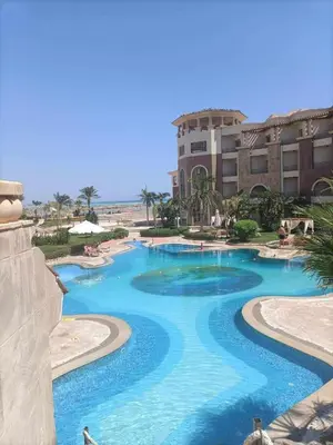 a swimming pool with blue water in front of a building at Royal Beach Hurghada in Hurghada