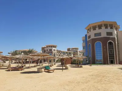a beach with chairs and umbrellas and a building at Royal Beach Hurghada in Hurghada