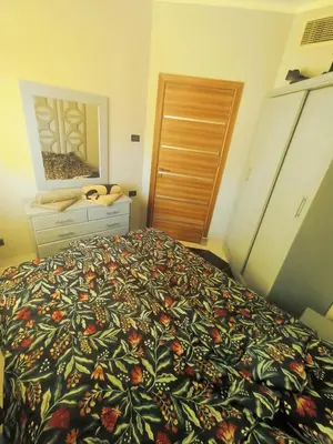a bedroom with a bed and a dresser and a door at Royal Beach Hurghada in Hurghada