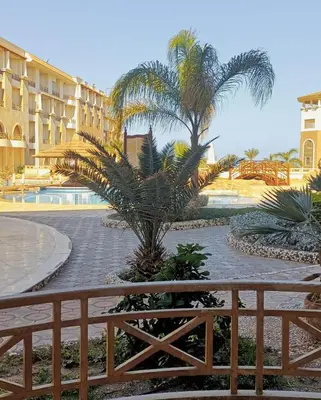 a view of a resort with palm trees and a fence at Royal Beach Hurghada in Hurghada