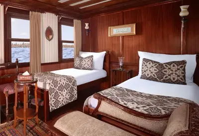 a bedroom with two beds and a table and a couch at JAZ Farouz El Nil III Nile Cruise - Every Saturday from Luxor for 07 & 05 Nights in Luxor