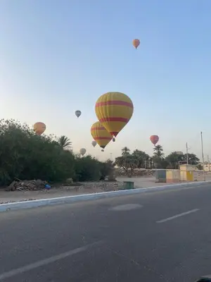 a group of hot air balloons flying over a road at Tibs mountain view in Al Aqālitah
