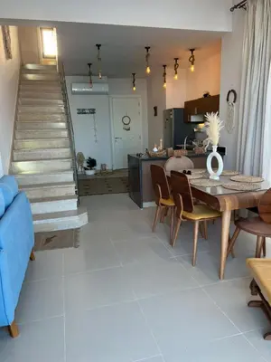 a living room with a table and chairs and a staircase at Luxury 4 bedroom villa - Cyan ElGouna in Hurghada