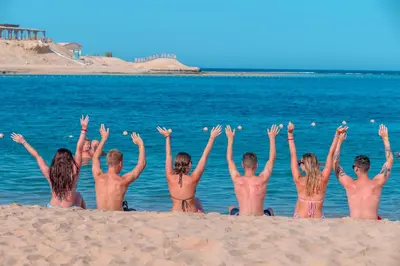 a group of people sitting on the beach with their hands up at Siva Golden Bay Makadi in Hurghada
