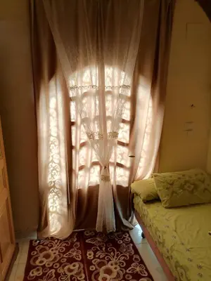 a bedroom with a curtain and a bed and a window at Djorf apartments in Al Aqālitah
