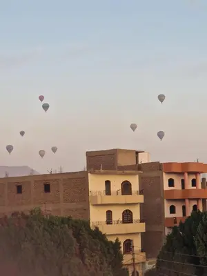 a group of hot air balloons flying over a building at Djorf apartments in Al Aqālitah