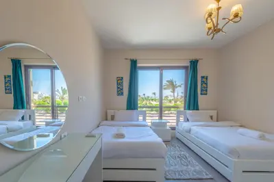 a bedroom with three beds and a mirror at Cozy 2BR in Cyan, El Gouna Swiming Pool Access in Hurghada