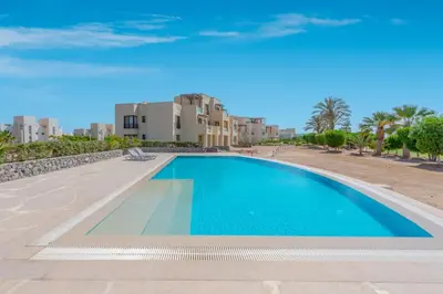 a swimming pool in a resort with buildings in the background at Cozy 2BR in Cyan, El Gouna Swiming Pool Access in Hurghada