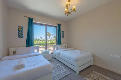 two beds in a room with a window at Cozy 2BR in Cyan, El Gouna Swiming Pool Access in Hurghada